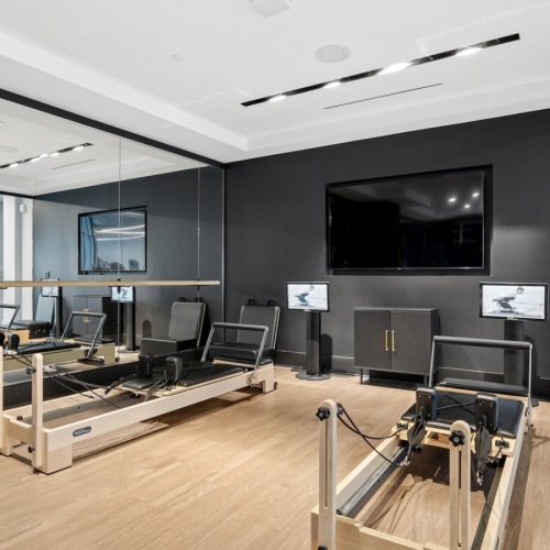 fitness center with row machines a wall mounted tv and mirrored wall